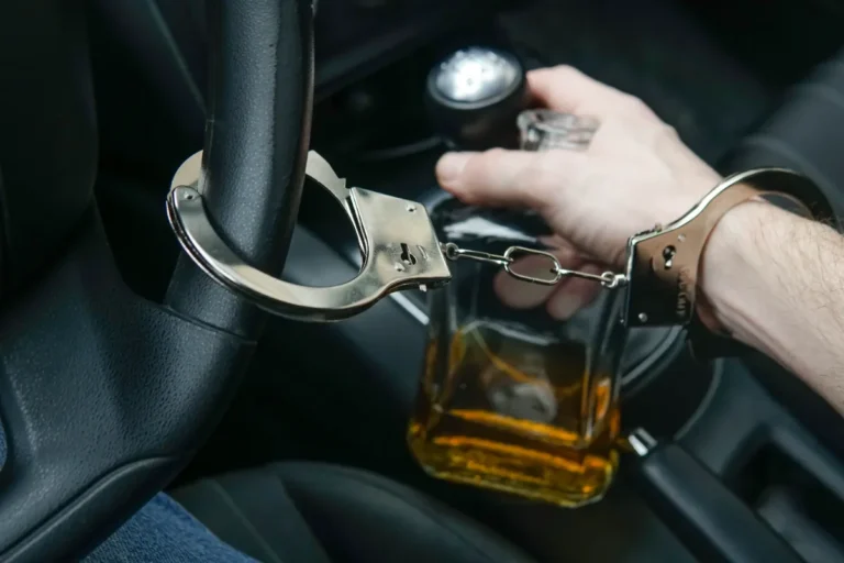 A man inside his car with a handcuff and a bottle of alcohol drink.